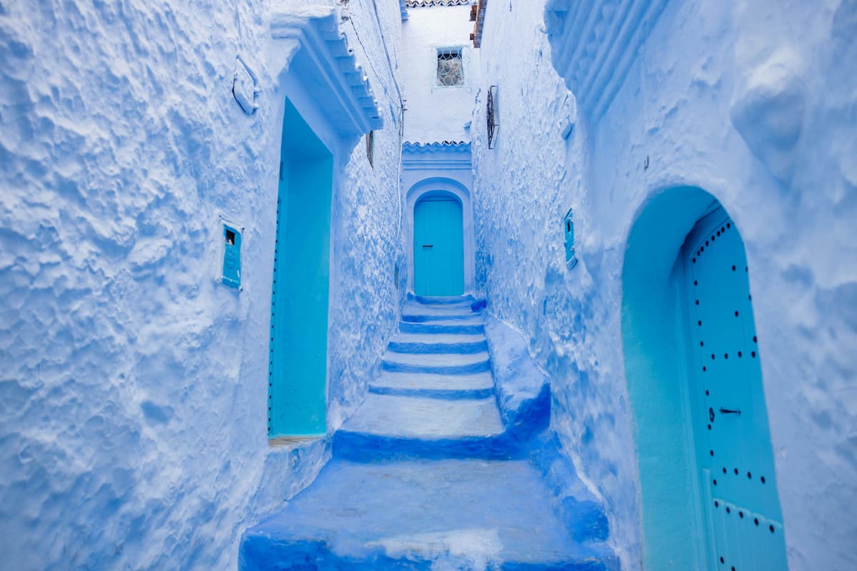 Chefchaouen blue medina alley with arched doorways, Morocco